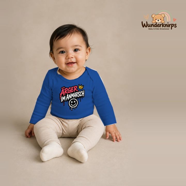 Babybody für Mädchen in Blau mit Motiv „Ärger im Anmarsch“, getragen von einem Kind – Wunderknirps.