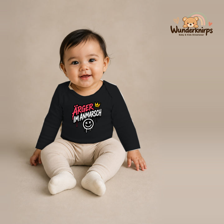Babybody für Mädchen in Schwarz mit Motiv „Ärger im Anmarsch“, getragen von einem Kind – Wunderknirps.