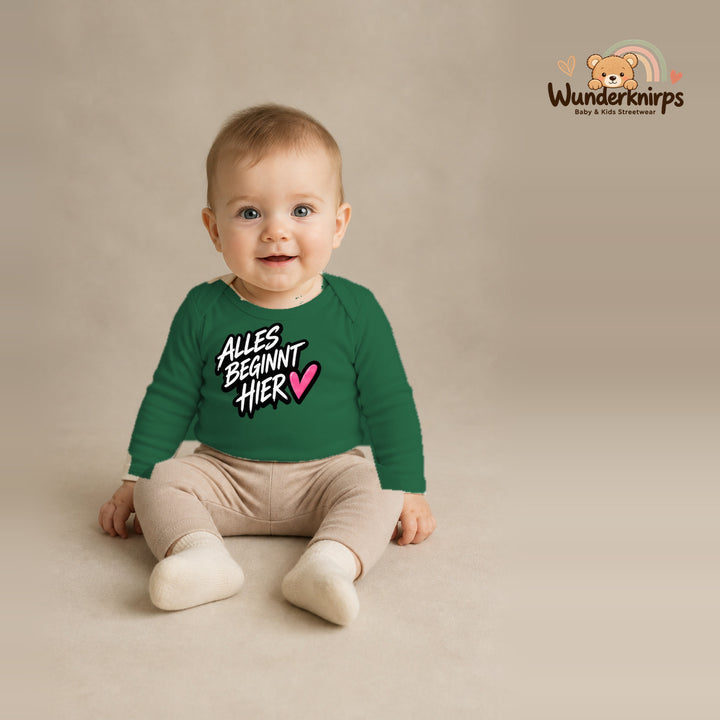 Babybody für Jungen in Grün mit Motiv „Alles beginnt hier“, getragen von einem Kind – Wunderknirps.