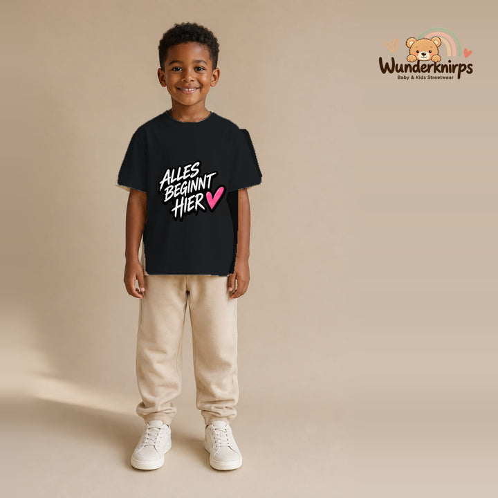 T-Shirt für Jungen in Schwarz mit Motiv „Alles beginnt hier“, getragen von einem Kind – Wunderknirps.