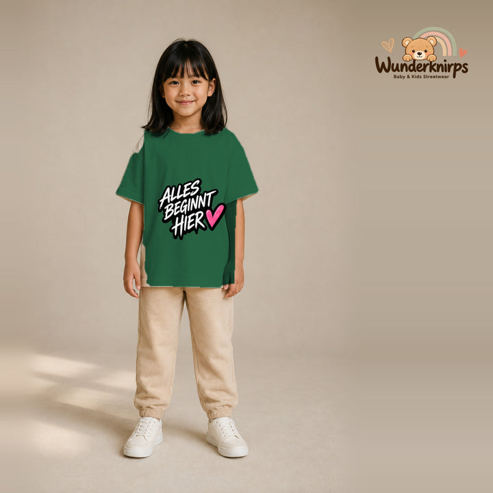 T-Shirt für Mädchen in Grün mit Motiv „Alles beginnt hier“, getragen von einem Kind – Wunderknirps.