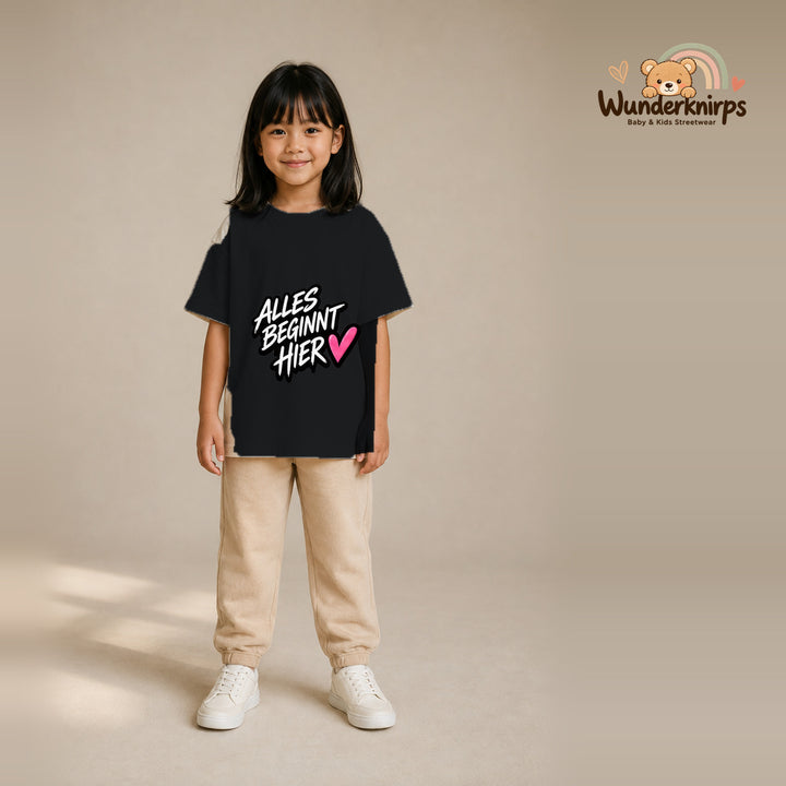 T-Shirt für Mädchen in Schwarz mit Motiv „Alles beginnt hier“, getragen von einem Kind – Wunderknirps.