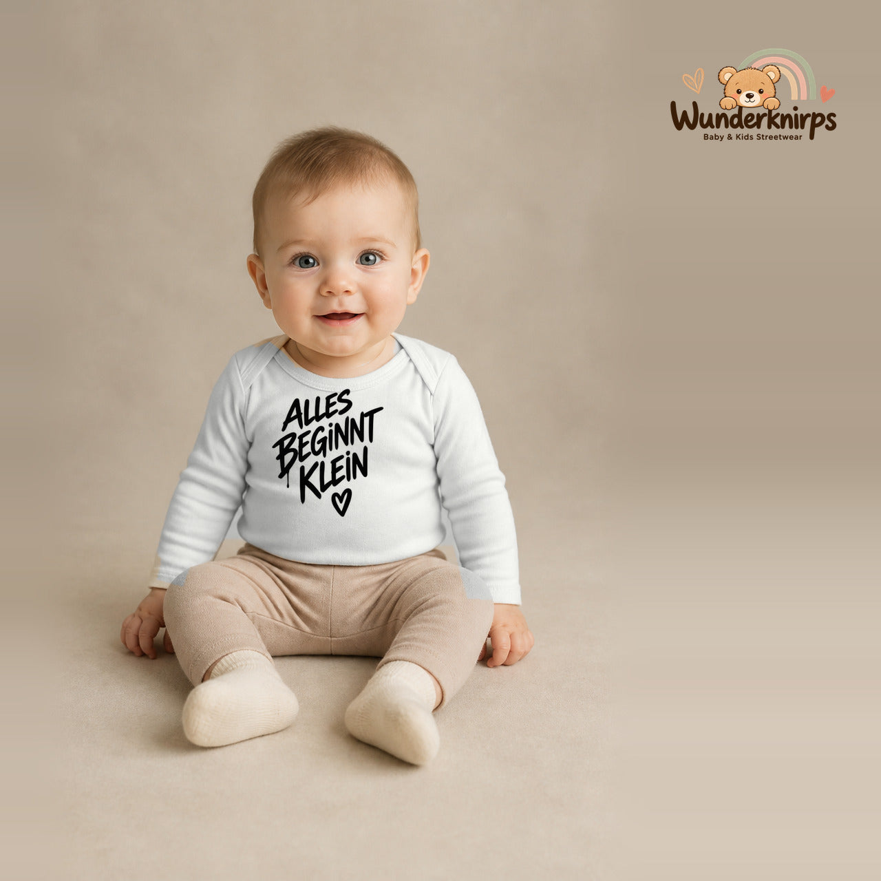 Babybody für Jungen in Weiß mit Motiv „Alles beginnt klein“, getragen von einem Kind – Wunderknirps.