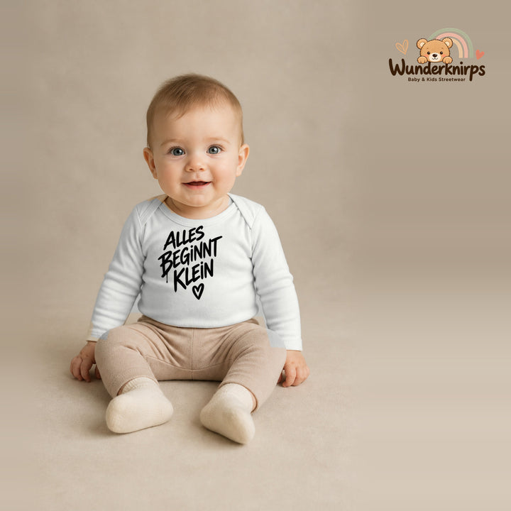 Babybody für Jungen in Weiß mit Motiv „Alles beginnt klein“, getragen von einem Kind – Wunderknirps.