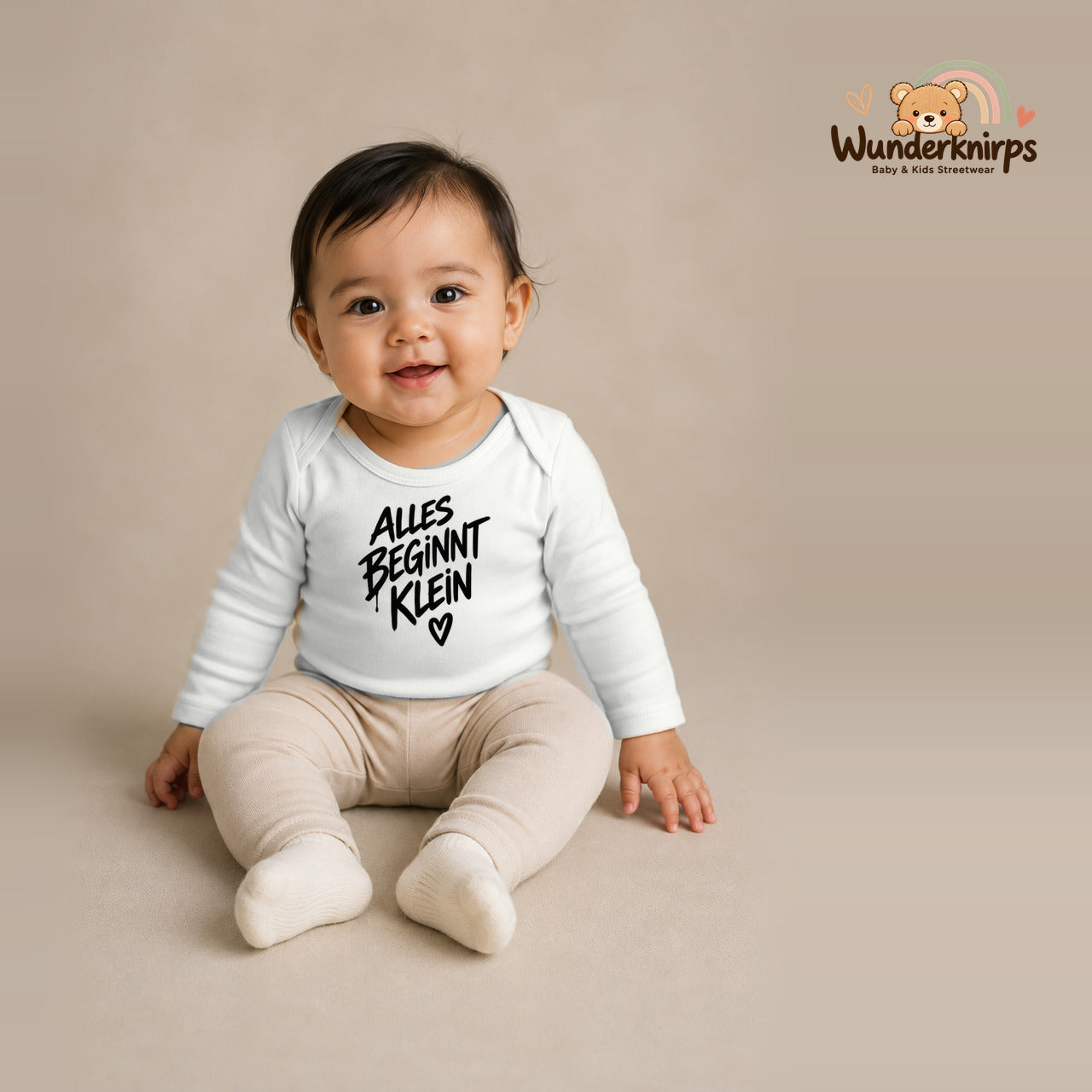 Babybody für Mädchen in Weiß mit Motiv „Alles beginnt klein“, getragen von einem Kind – Wunderknirps.