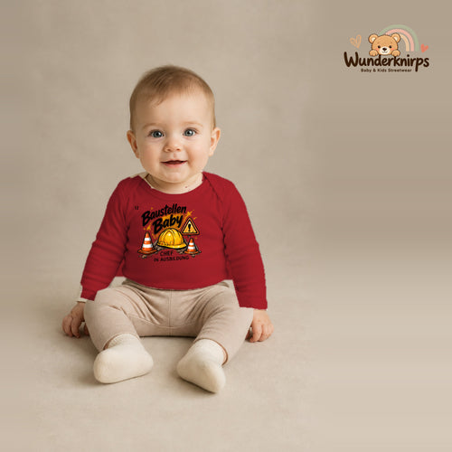 Babybody für Jungen in Rot mit Motiv „Baustellenbaby“, getragen von einem Kind – Wunderknirps.
