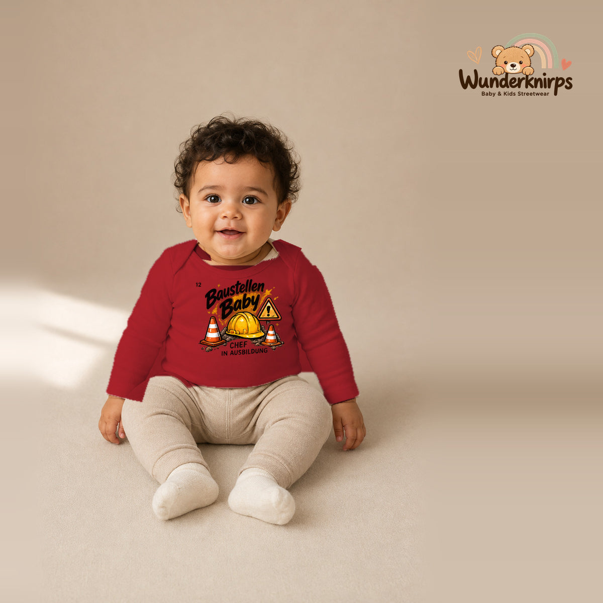 Babybody für Jungen in Rot mit Motiv „Baustellenbaby“, getragen von einem Kind – Wunderknirps.