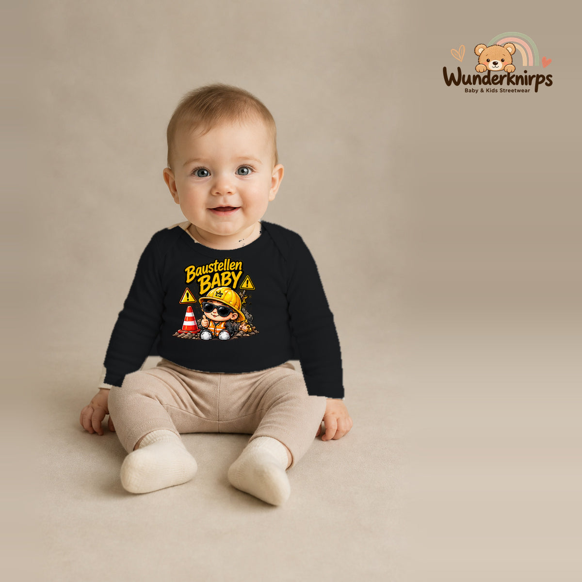 Babybody für Jungen in Schwarz mit Motiv „Baustellenbaby“, getragen von einem Kind – Wunderknirps.
