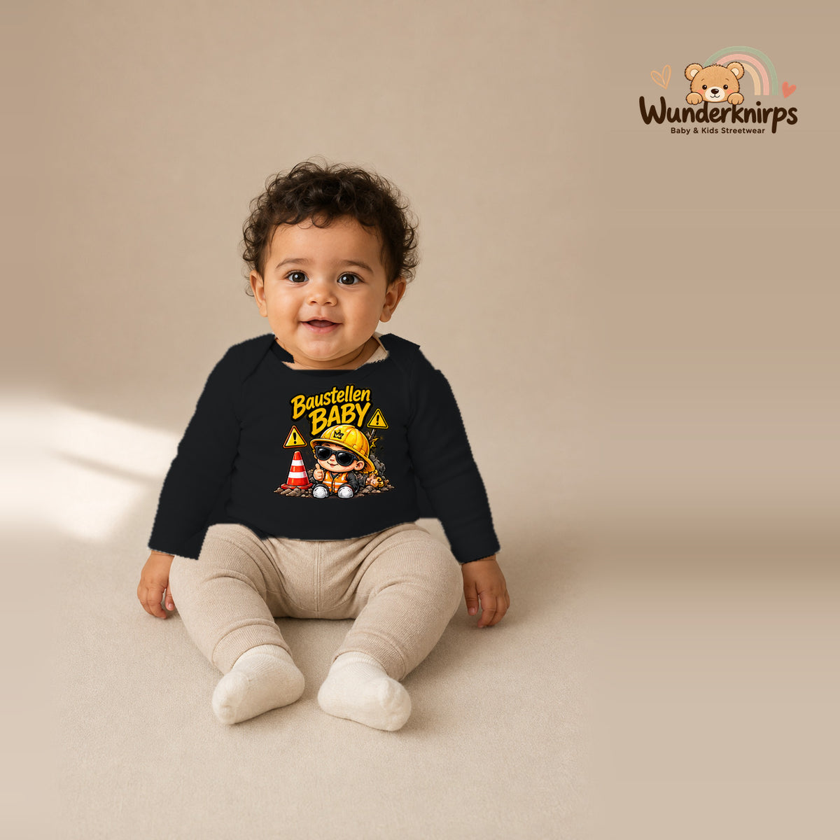Babybody für Jungen in Schwarz mit Motiv „Baustellenbaby“, getragen von einem Kind – Wunderknirps.