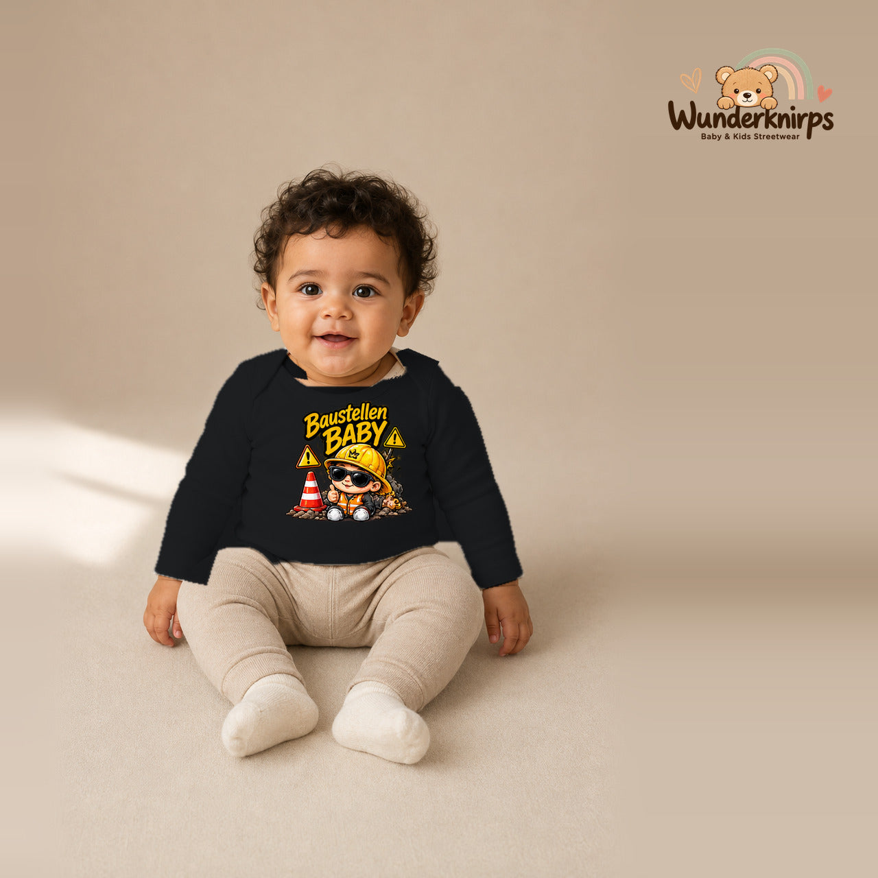 Babybody für Jungen in Schwarz mit Motiv „Baustellenbaby“, getragen von einem Kind – Wunderknirps.