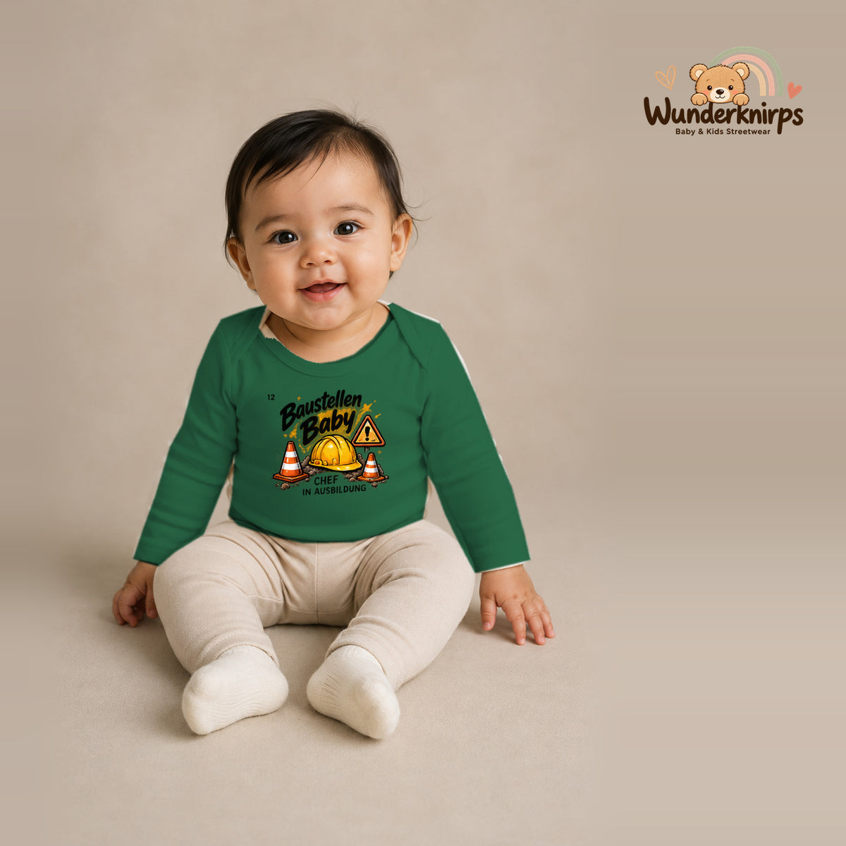 Babybody für Mädchen in Grün mit Motiv „Baustellenbaby“, getragen von einem Kind – Wunderknirps.