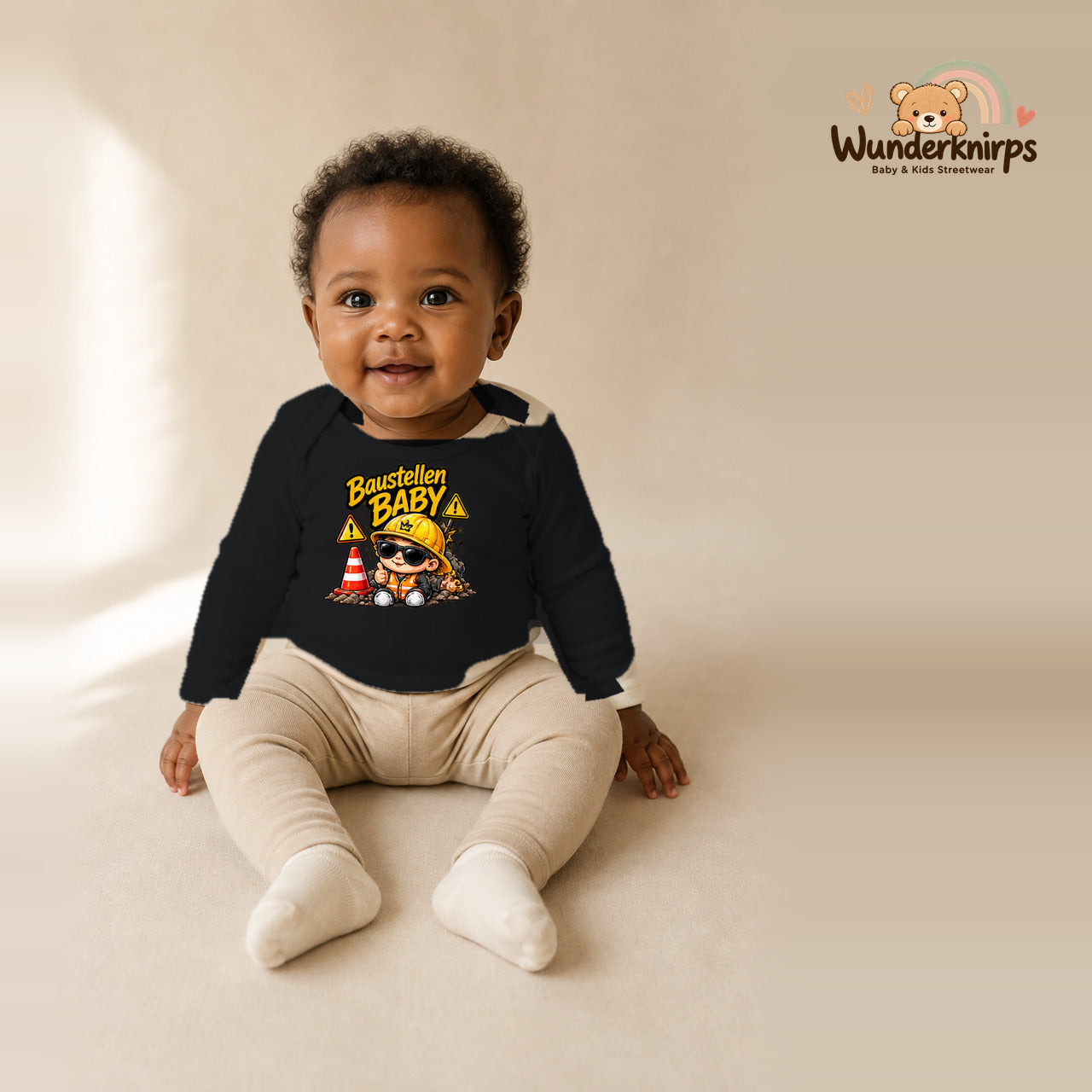 Babybody für Mädchen in Schwarz mit Motiv „Baustellenbaby“, getragen von einem Kind – Wunderknirps.