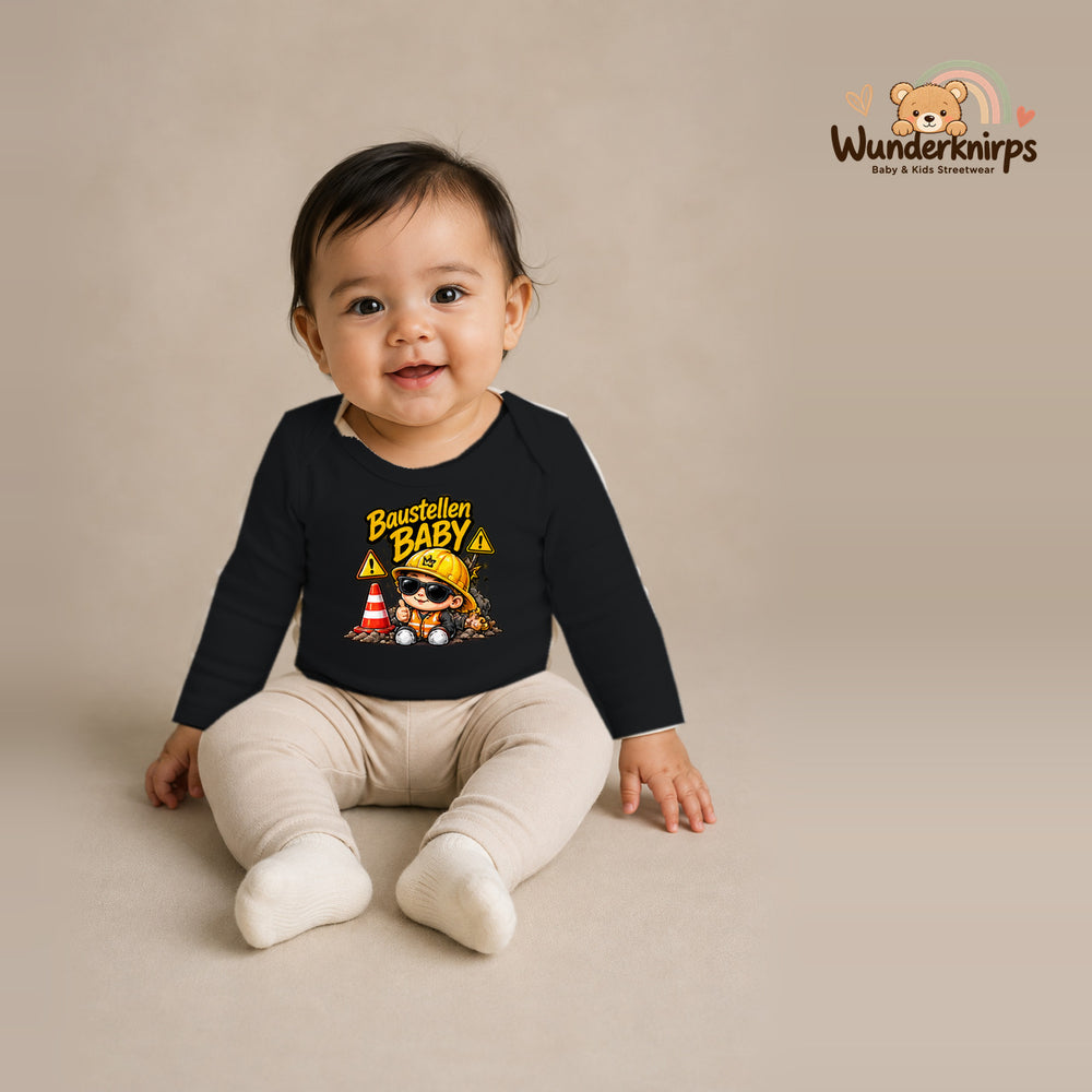 Babybody für Mädchen in Schwarz mit Motiv „Baustellenbaby“, getragen von einem Kind – Wunderknirps.