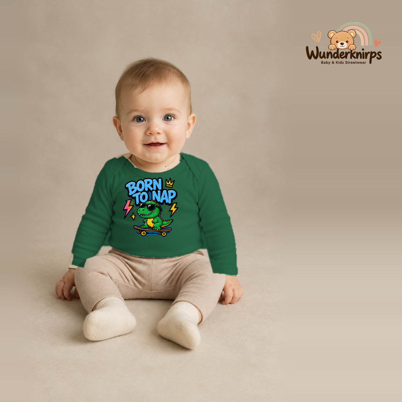 Babybody für Jungen in Grün mit Motiv „Born to Nap“, getragen von einem Kind – Wunderknirps.