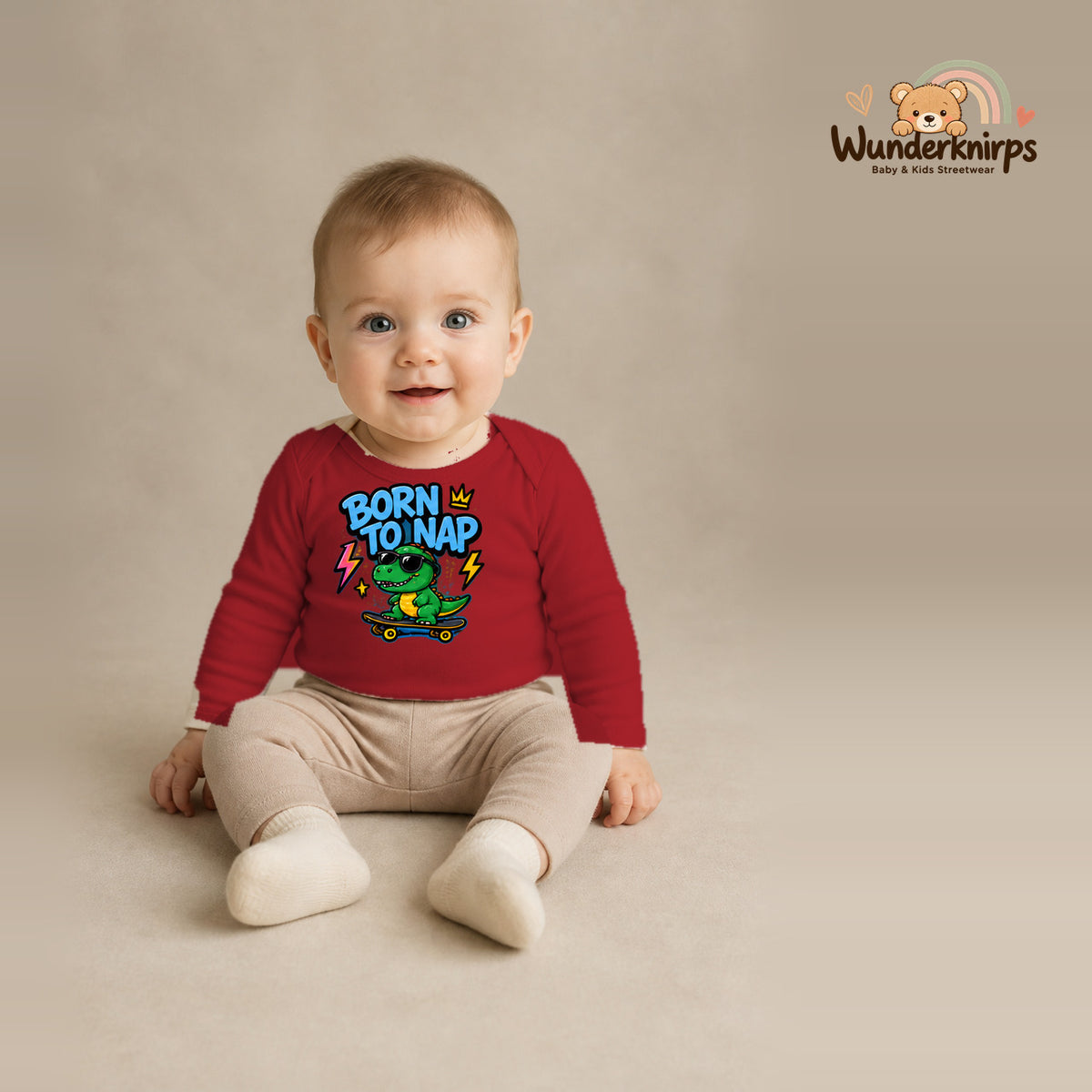 Babybody für Jungen in Rot mit Motiv „Born to Nap“, getragen von einem Kind – Wunderknirps.
