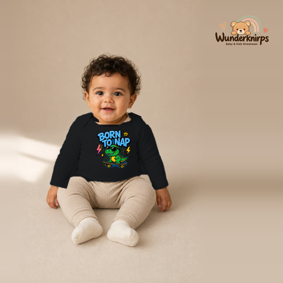 Babybody für Jungen in Schwarz mit Motiv „Born to Nap“, getragen von einem Kind – Wunderknirps.