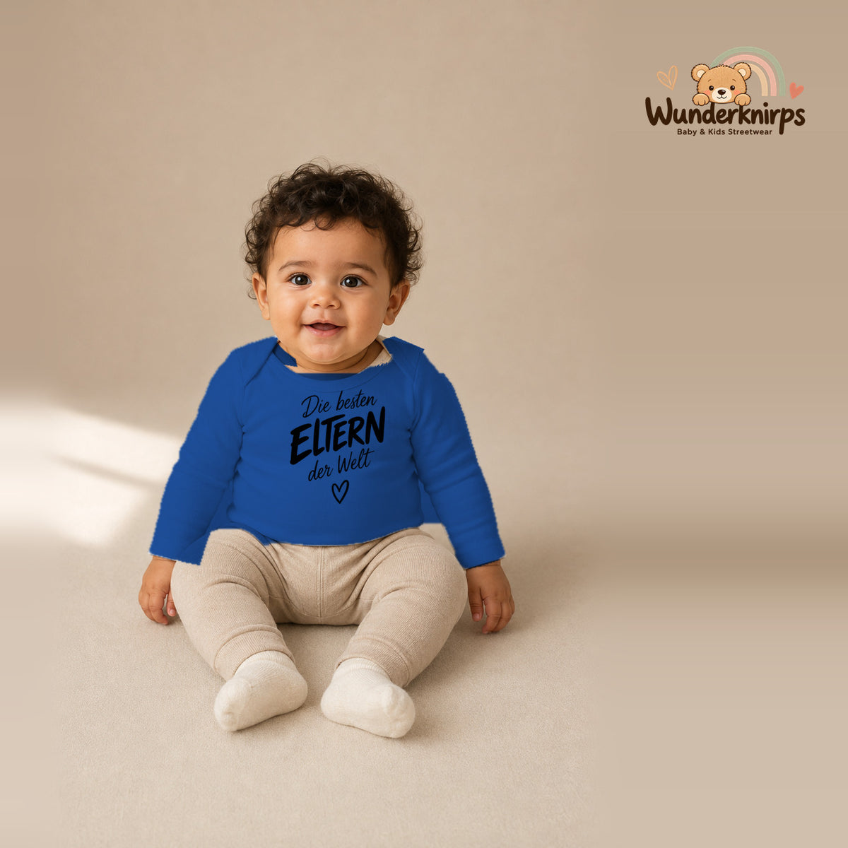 Babybody für Jungen in Blau mit Motiv „Die besten Eltern“, getragen von einem Kind – Wunderknirps.