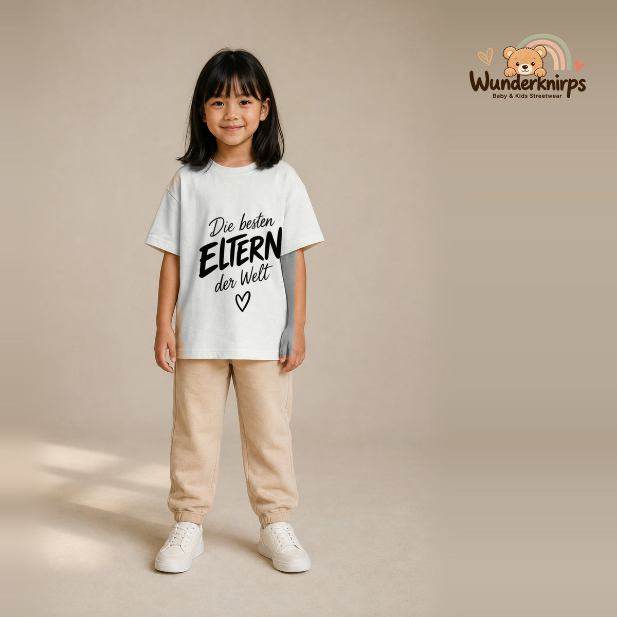 T-Shirt für Mädchen in Weiß mit Motiv „Die besten Eltern“, getragen von einem Kind – Wunderknirps.
