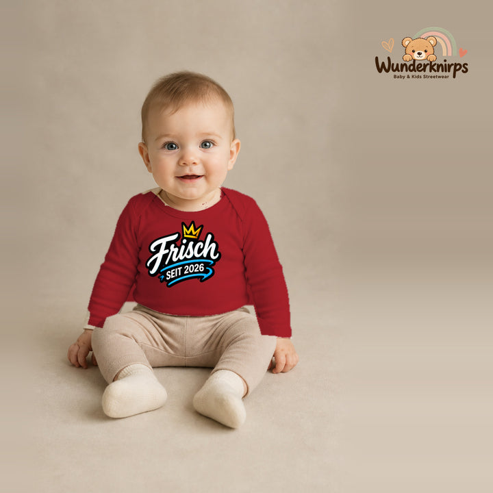 Babybody für Jungen in Rot mit Motiv „Frisch seit 2026“, getragen von einem Kind – Wunderknirps.