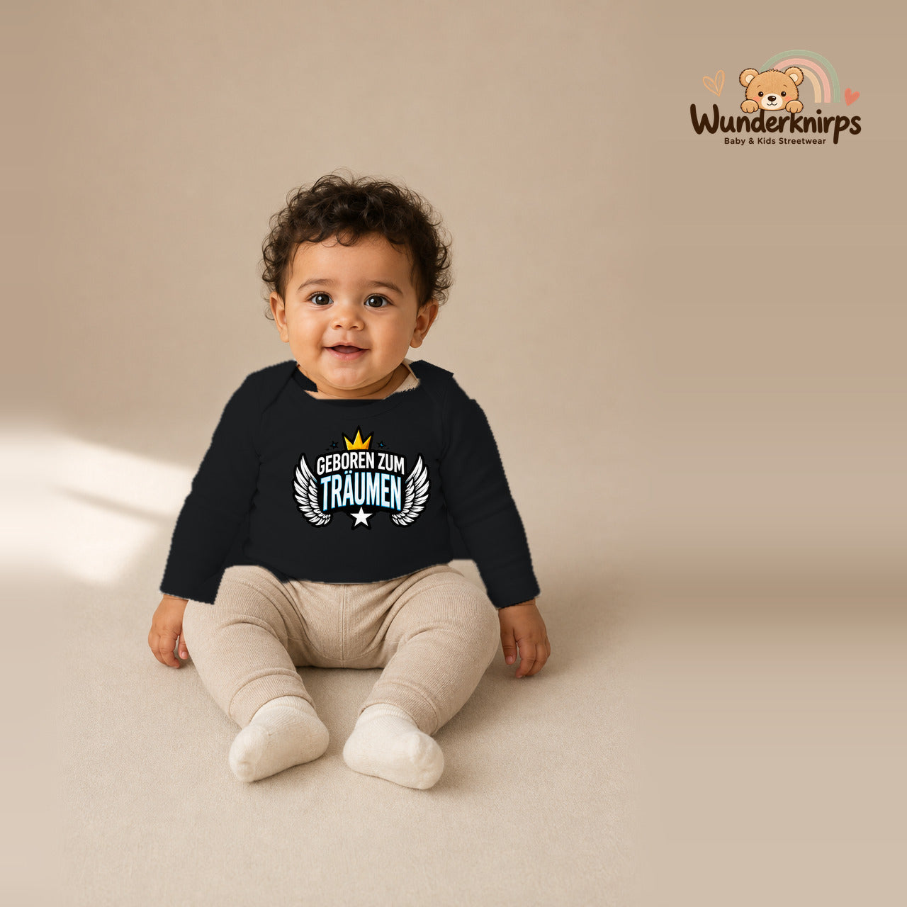 Babybody für Jungen in Schwarz mit Motiv „Geboren zum Träumen“, getragen von einem Kind – Wunderknirps.