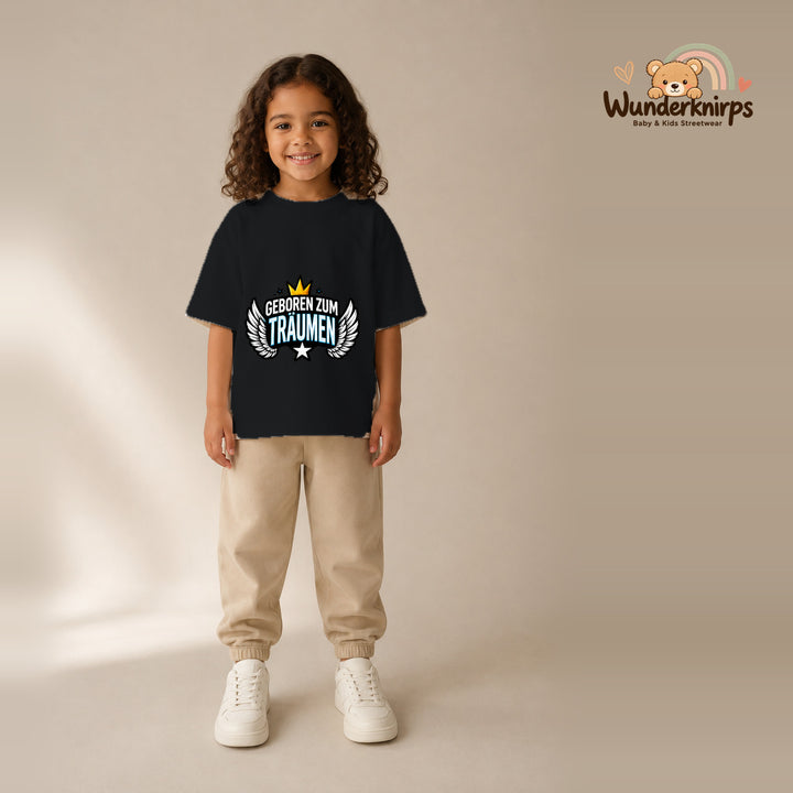 T-Shirt für Mädchen in Schwarz mit Motiv „Geboren zum Träumen“, getragen von einem Kind – Wunderknirps.