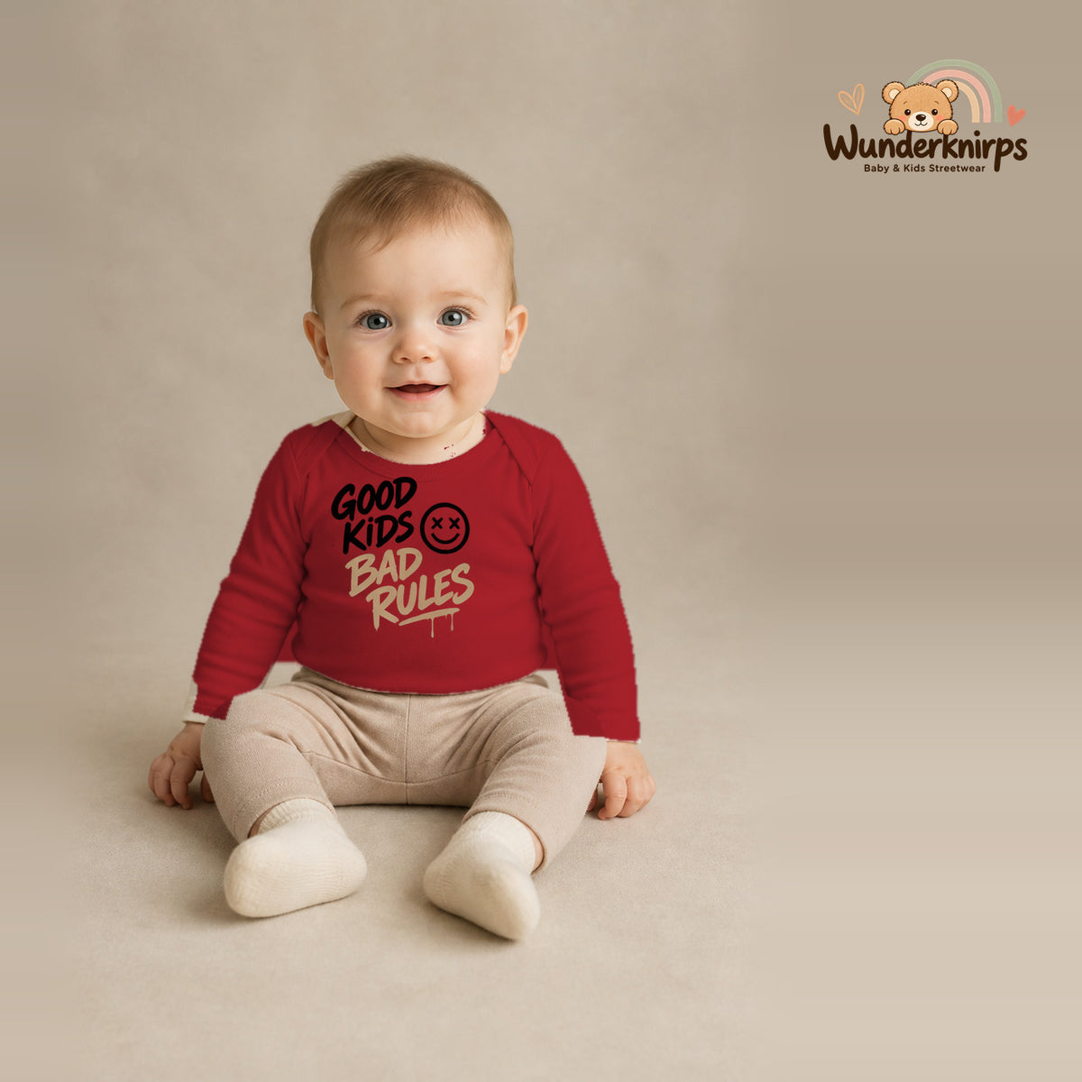 Babybody für Jungen in Rot mit Motiv „Good Kids Bad Rules“, getragen von einem Kind – Wunderknirps.