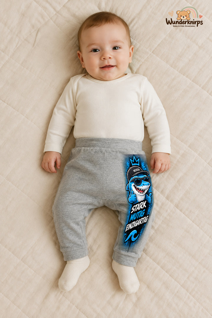 Hai Alltagsheld – Stark mutig einzigartig – Babyhose für Jungen: Grau meliert mit Hai-Druck am Hosenbein – Wunderknirps.