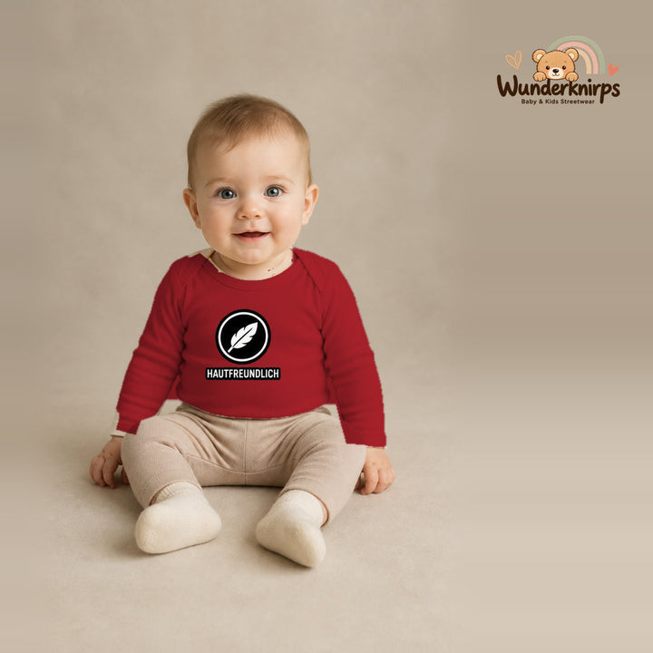 Babybody für Jungen in Rot mit Motiv „Hautfreundlich“, getragen von einem Kind – Wunderknirps.