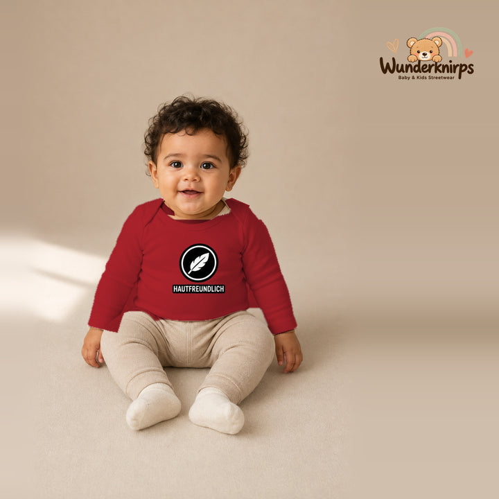 Babybody für Jungen in Rot mit Motiv „Hautfreundlich“, getragen von einem Kind – Wunderknirps.