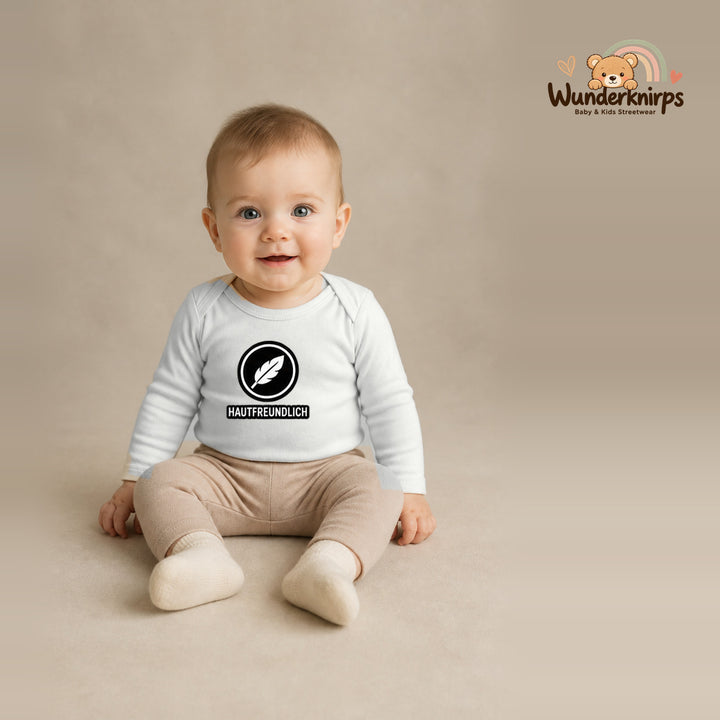 Babybody für Jungen in Weiß mit Motiv „Hautfreundlich“, getragen von einem Kind – Wunderknirps.