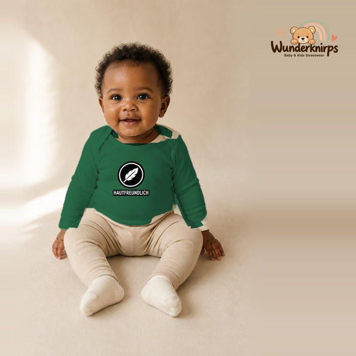 Babybody für Mädchen in Grün mit Motiv „Hautfreundlich“, getragen von einem Kind – Wunderknirps.
