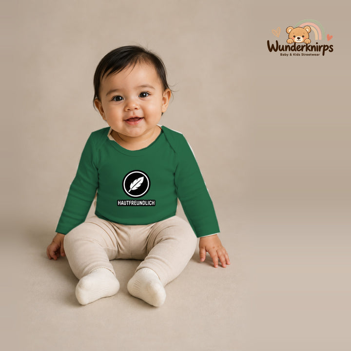 Babybody für Mädchen in Grün mit Motiv „Hautfreundlich“, getragen von einem Kind – Wunderknirps.
