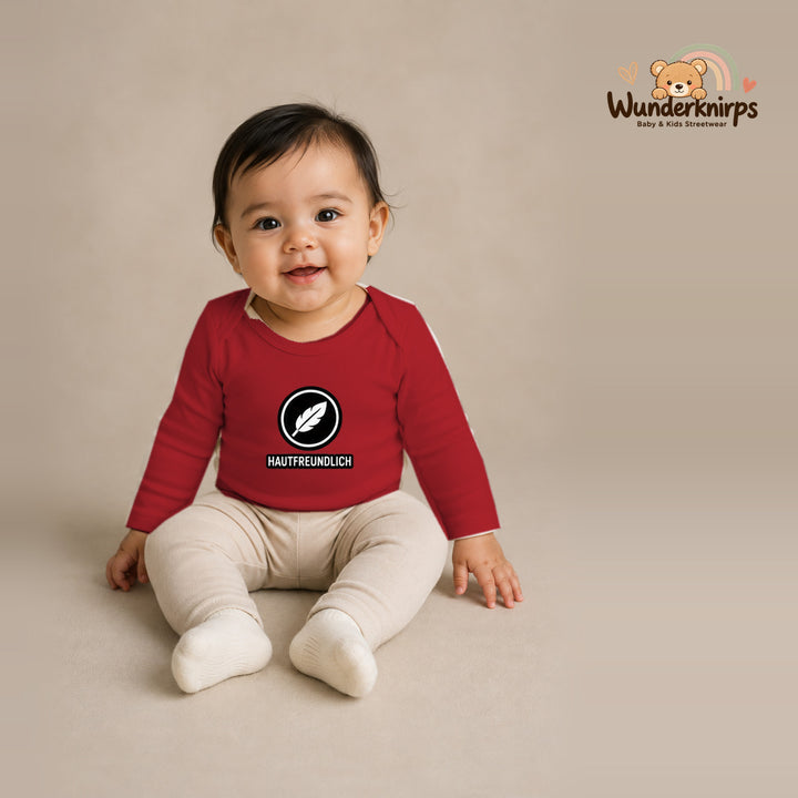 Babybody für Mädchen in Rot mit Motiv „Hautfreundlich“, getragen von einem Kind – Wunderknirps.