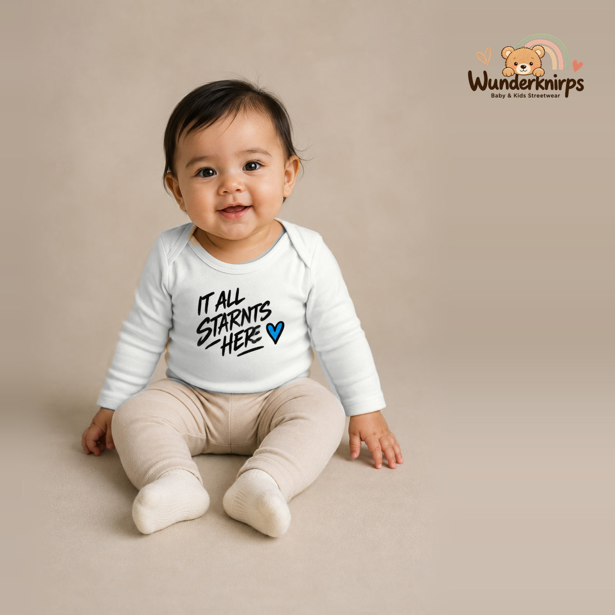 Babybody für Mädchen in Weiß mit Motiv „It all starts here“, getragen von einem Kind – Wunderknirps.