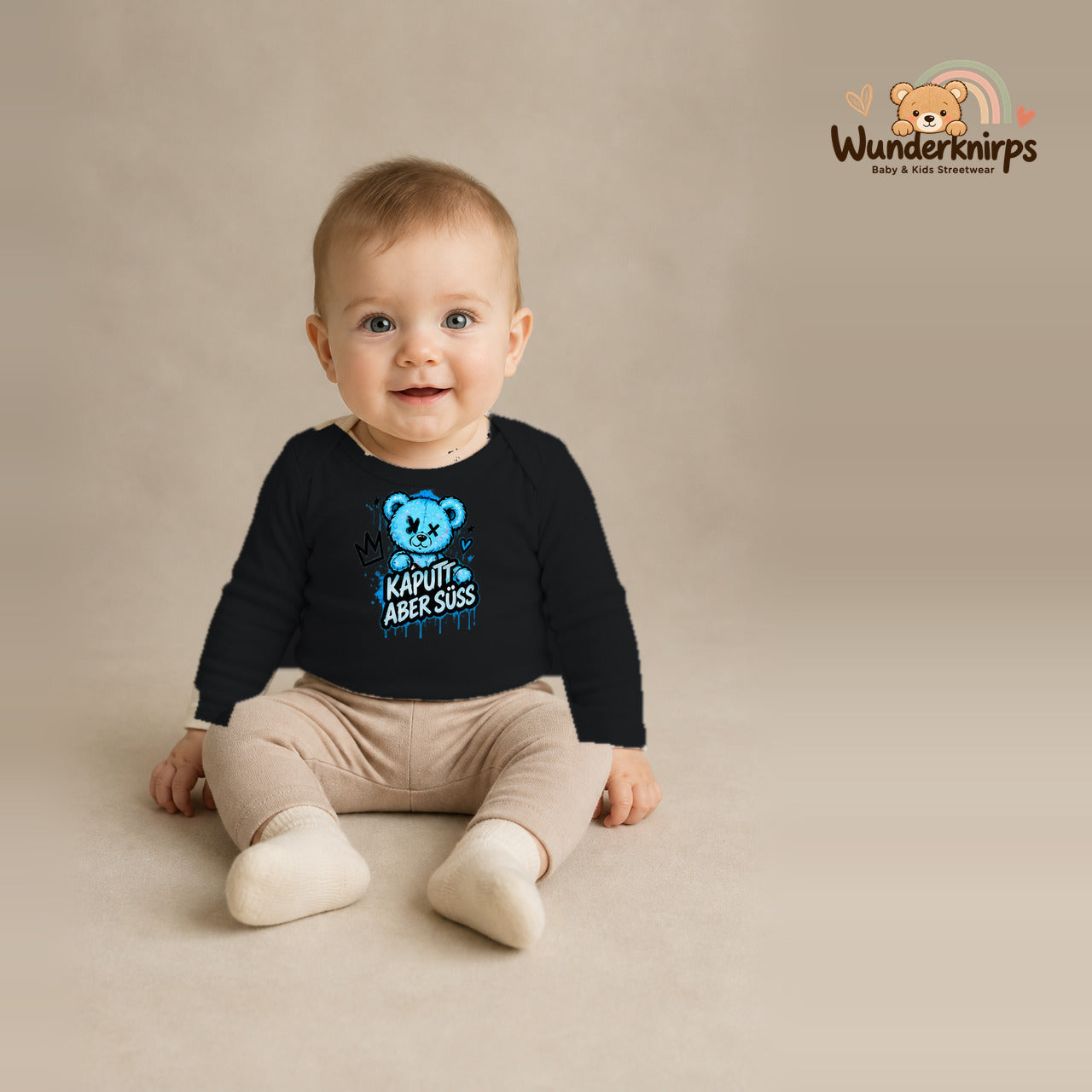 Babybody für Jungen in Schwarz mit Motiv „Kaputt aber süß“, getragen von einem Kind – Wunderknirps.