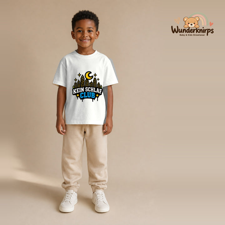 T-Shirt für Jungen in Weiß mit Motiv „Kein Schlaf Club“, getragen von einem Kind – Wunderknirps.