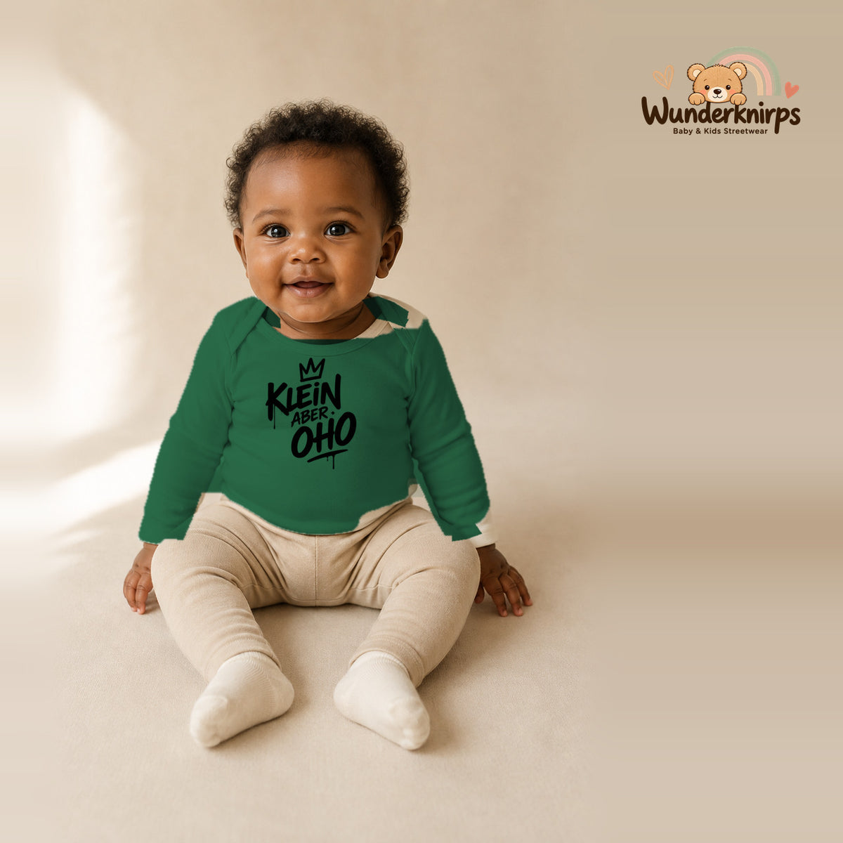 Babybody für Mädchen in Grün mit Motiv „Klein aber oho“, getragen von einem Kind – Wunderknirps.