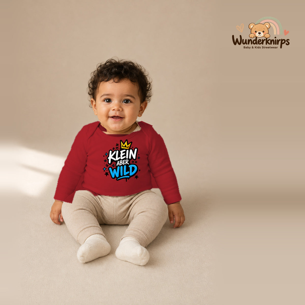 Babybody für Jungen in Rot mit Motiv „Klein aber wild“, getragen von einem Kind – Wunderknirps.