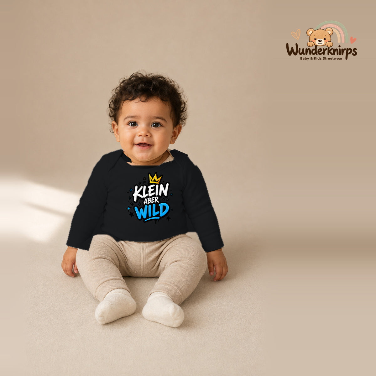 Babybody für Jungen in Schwarz mit Motiv „Klein aber wild“, getragen von einem Kind – Wunderknirps.