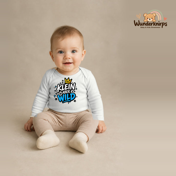 Babybody für Jungen in Weiß mit Motiv „Klein aber wild“, getragen von einem Kind – Wunderknirps.
