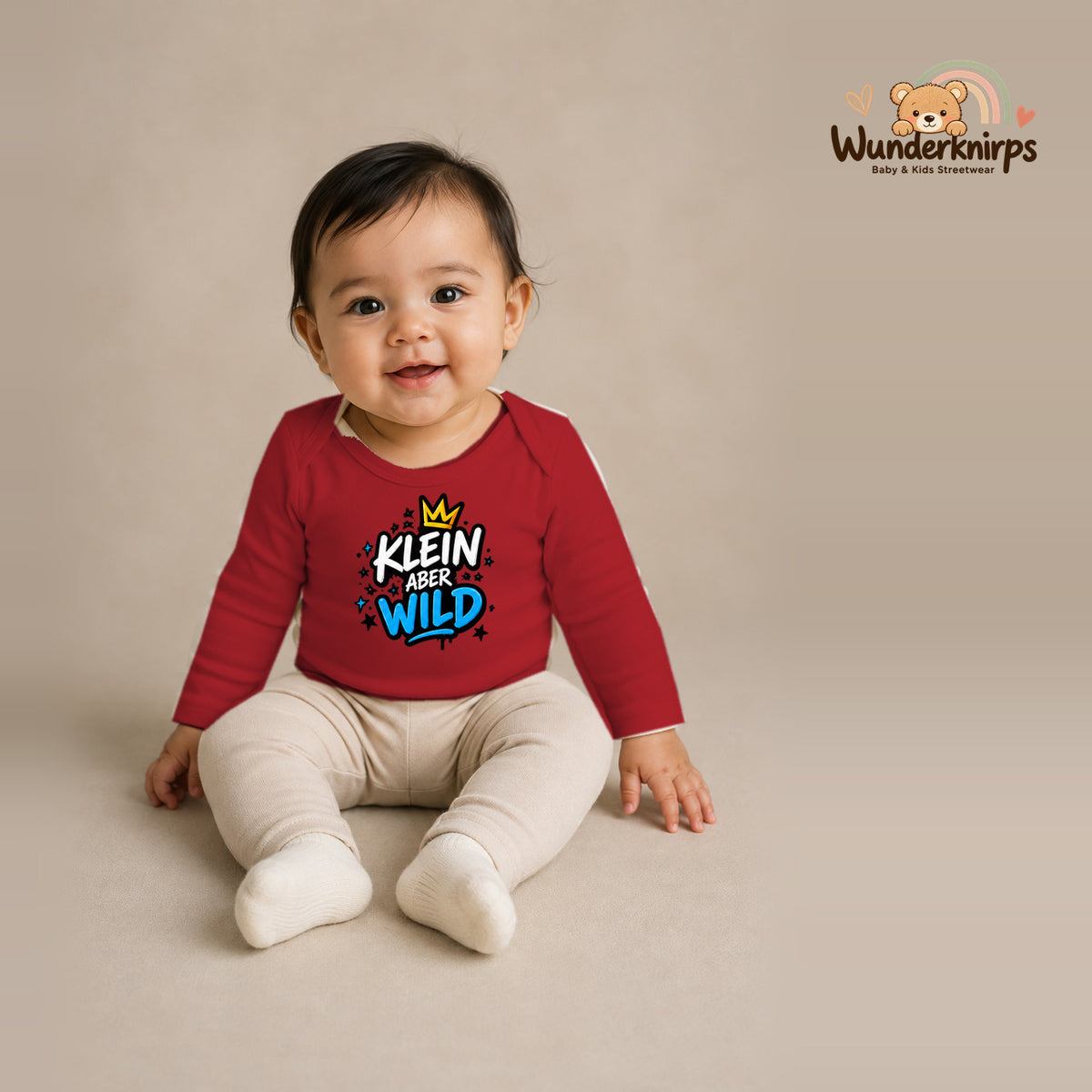 Babybody für Mädchen in Rot mit Motiv „Klein aber wild“, getragen von einem Kind – Wunderknirps.
