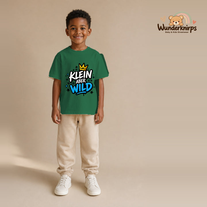 T-Shirt für Jungen in Grün mit Motiv „Klein aber wild“, getragen von einem Kind – Wunderknirps.