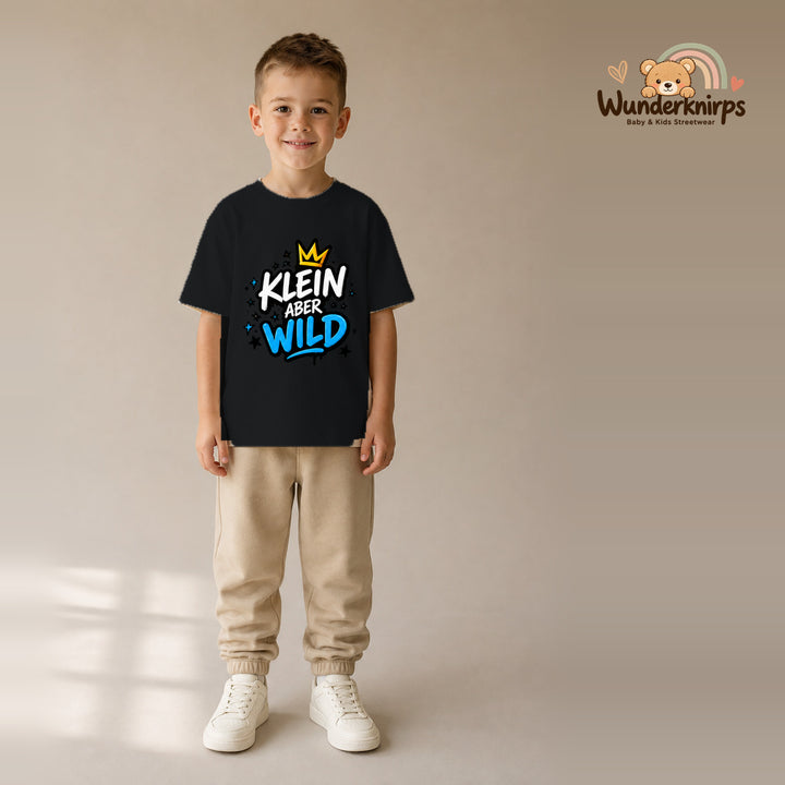 T-Shirt für Jungen in Schwarz mit Motiv „Klein aber wild“, getragen von einem Kind – Wunderknirps.