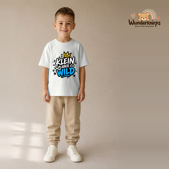 T-Shirt für Jungen in Weiß mit Motiv „Klein aber wild“, getragen von einem Kind – Wunderknirps.