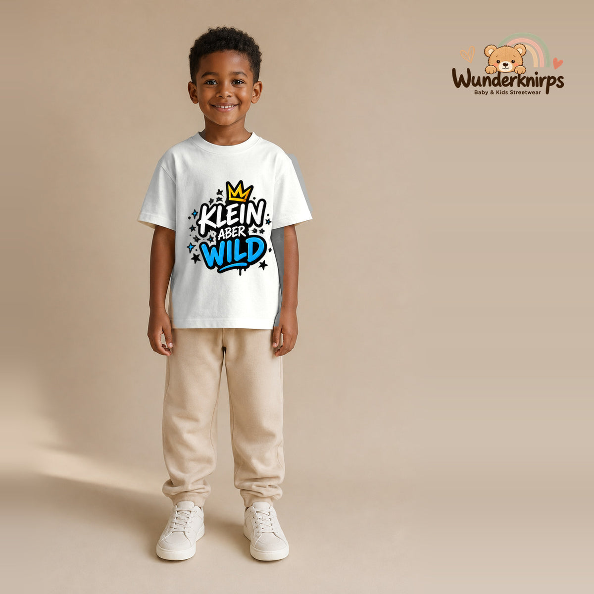 T-Shirt für Jungen in Weiß mit Motiv „Klein aber wild“, getragen von einem Kind – Wunderknirps.