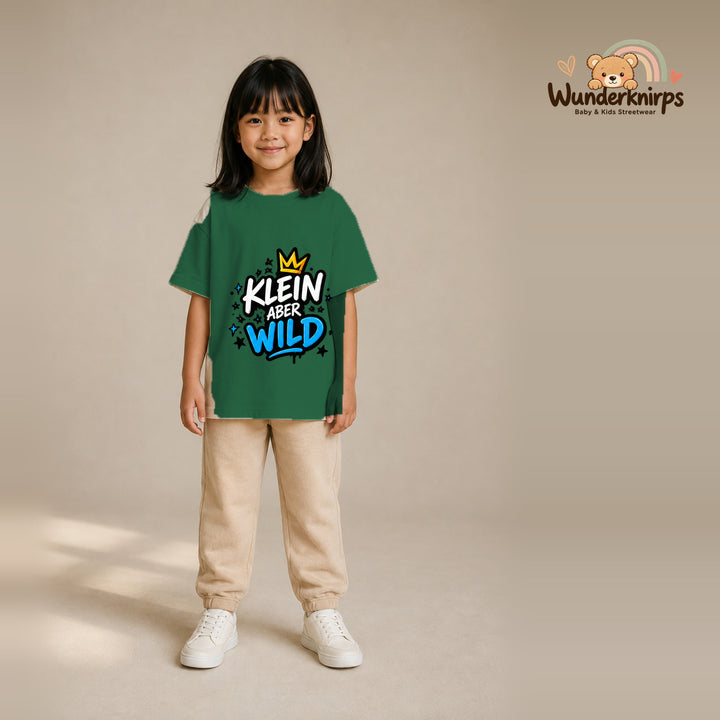 T-Shirt für Mädchen in Grün mit Motiv „Klein aber wild“, getragen von einem Kind – Wunderknirps.