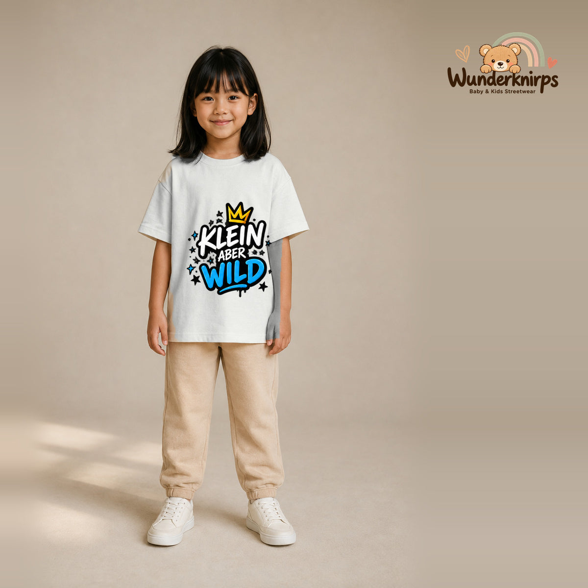 T-Shirt für Mädchen in Weiß mit Motiv „Klein aber wild“, getragen von einem Kind – Wunderknirps.
