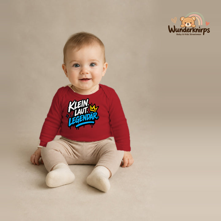 Babybody für Jungen in Rot mit Motiv „Klein laut legendär“, getragen von einem Kind – Wunderknirps.