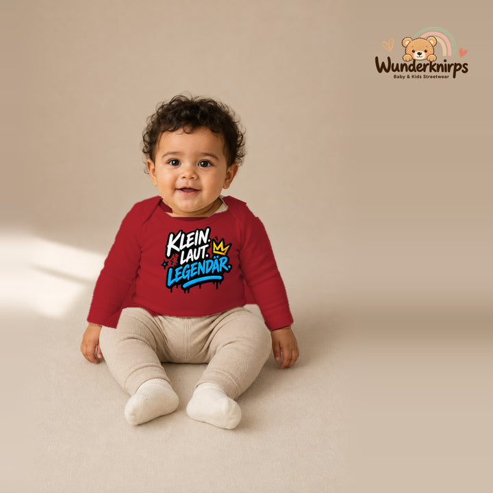Babybody für Jungen in Rot mit Motiv „Klein laut legendär“, getragen von einem Kind – Wunderknirps.