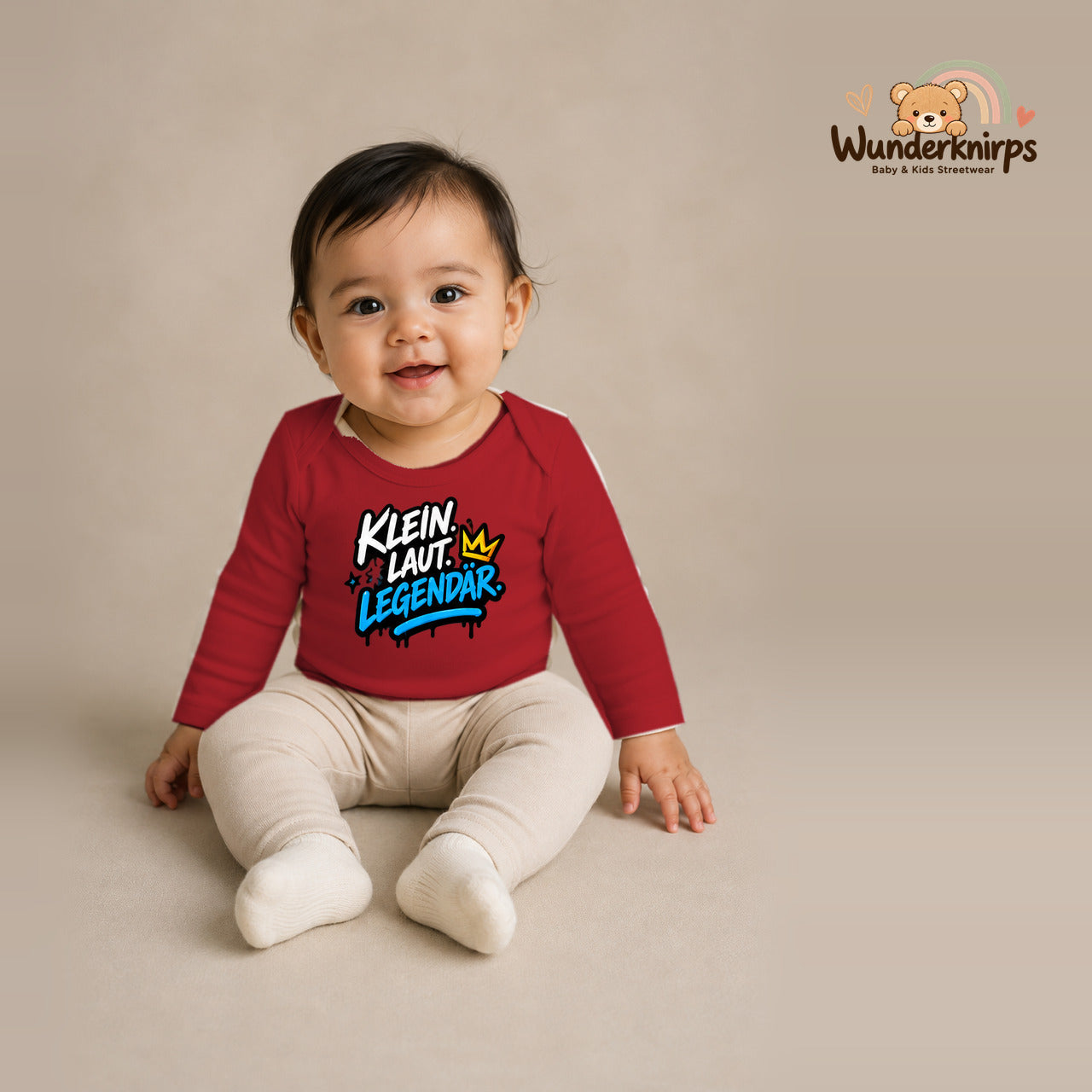 Babybody für Mädchen in Rot mit Motiv „Klein laut legendär“, getragen von einem Kind – Wunderknirps.